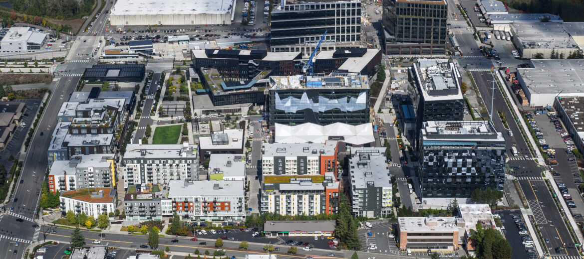 Aerial view of the site taken in 2023 showing a vibrant, thriving community with 800,000 square feet of  LEED-certified buildings, including residential, office  and retail as well as parks and new East Link light rail  station.